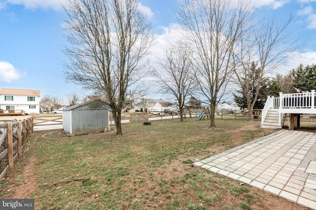 view of yard with an outbuilding, a playground, a shed, a fenced backyard, and a wooden deck