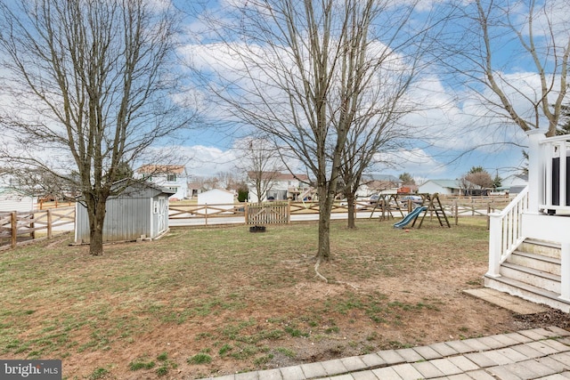 view of yard with a playground, an outdoor structure, a storage shed, and fence