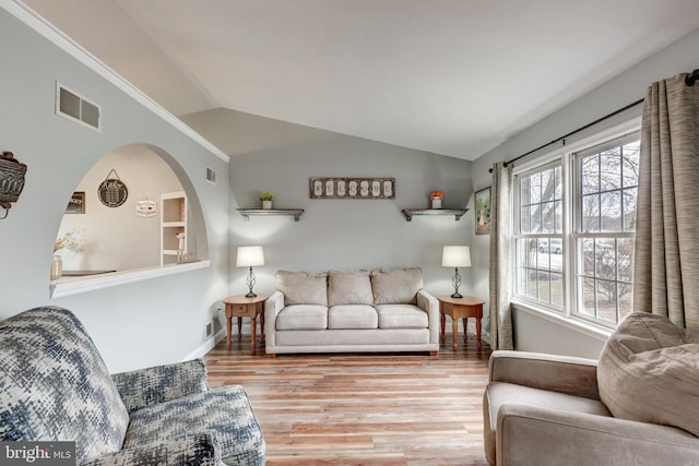 living room with lofted ceiling, visible vents, baseboards, and wood finished floors