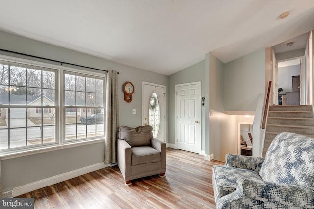 living area with light wood-style flooring, stairs, baseboards, and vaulted ceiling