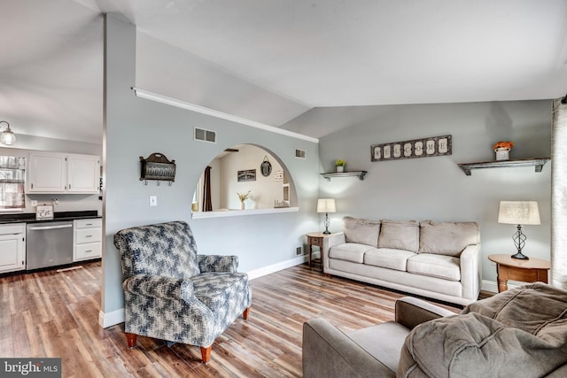 living area featuring vaulted ceiling, wood finished floors, visible vents, and baseboards