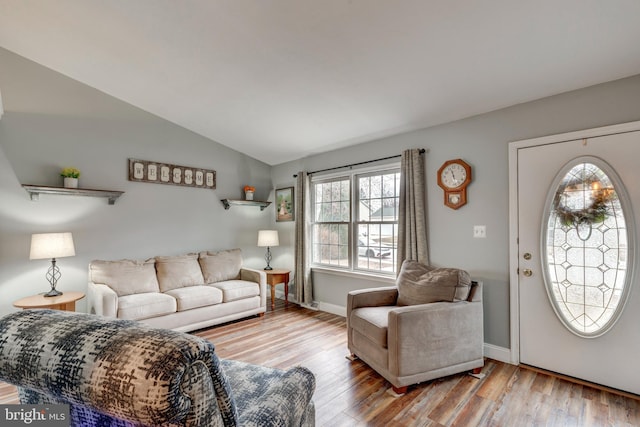 living room featuring vaulted ceiling, baseboards, and wood finished floors