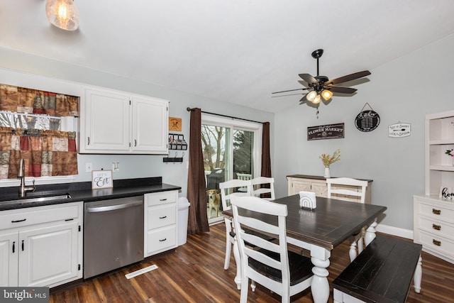 kitchen featuring dark countertops, dark wood-type flooring, white cabinets, a sink, and dishwasher