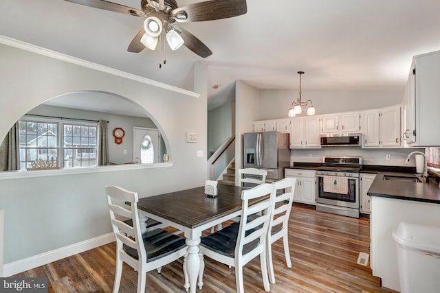 dining room with vaulted ceiling, dark wood finished floors, baseboards, and ceiling fan with notable chandelier