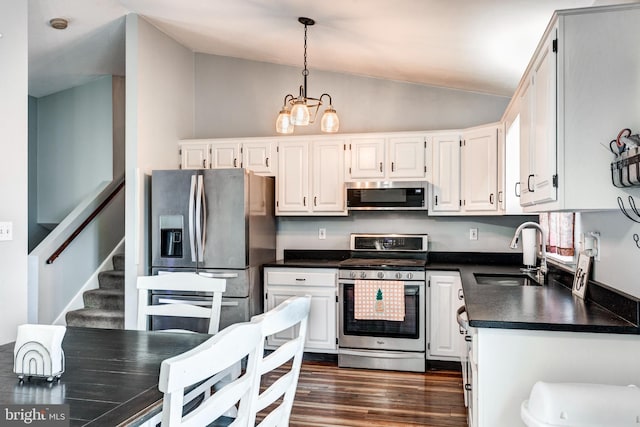 kitchen with lofted ceiling, a sink, white cabinets, appliances with stainless steel finishes, and dark countertops