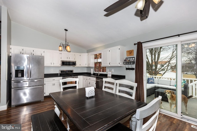 interior space with lofted ceiling, ceiling fan with notable chandelier, and dark wood finished floors