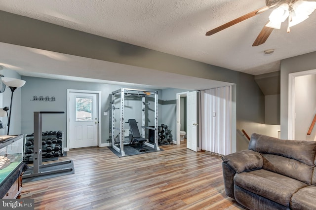 workout area featuring light wood-type flooring and a textured ceiling