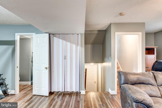 living room featuring a textured ceiling, stairway, wood finished floors, and baseboards