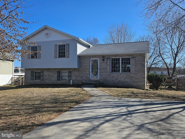 split level home featuring a front yard and brick siding