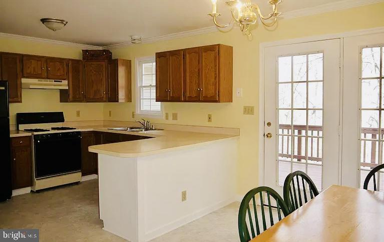 kitchen with range with gas cooktop, light countertops, hanging light fixtures, a sink, and under cabinet range hood