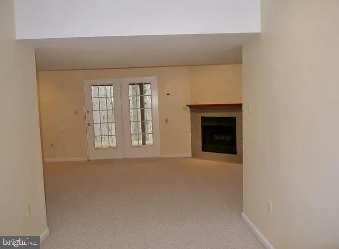 unfurnished living room with carpet flooring, a fireplace, and baseboards