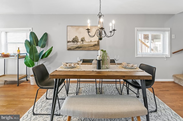 dining area with stairs, an inviting chandelier, baseboards, and wood finished floors