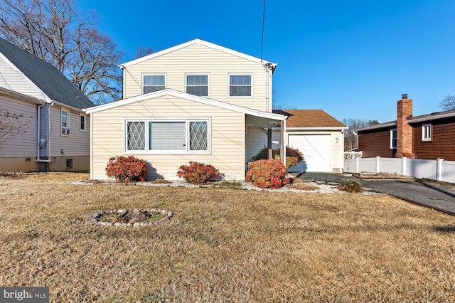 traditional-style house with driveway, fence, and a front yard