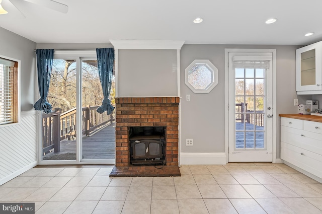 unfurnished living room with recessed lighting, a wood stove, baseboards, and light tile patterned floors