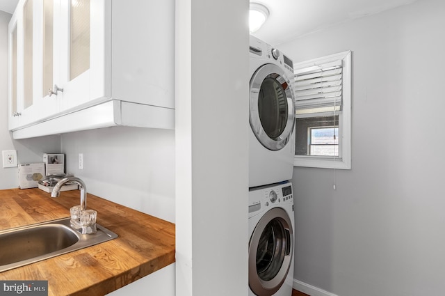 washroom with stacked washer and dryer and a sink