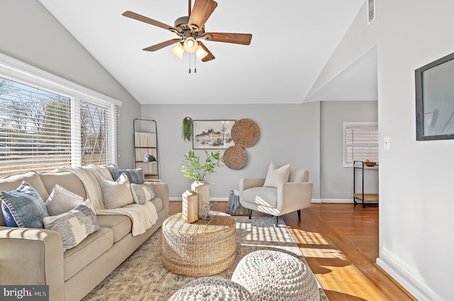 living area featuring lofted ceiling, visible vents, a ceiling fan, wood finished floors, and baseboards