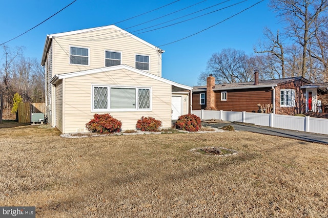 traditional-style house with an attached garage, fence, and a front yard