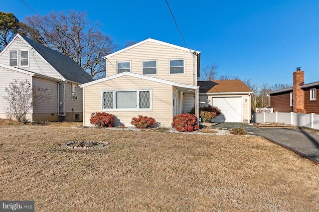 traditional-style home with aphalt driveway, a front lawn, fence, and a garage