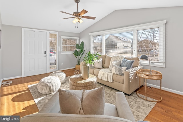 living area featuring lofted ceiling, baseboards, a ceiling fan, and wood finished floors