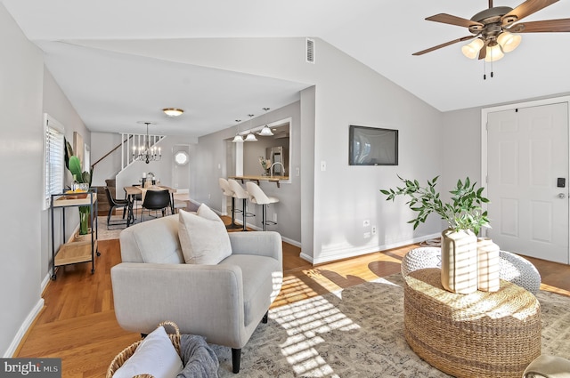 living room with visible vents, baseboards, wood finished floors, vaulted ceiling, and ceiling fan with notable chandelier