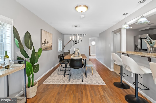 dining space featuring a notable chandelier, wood finished floors, and baseboards