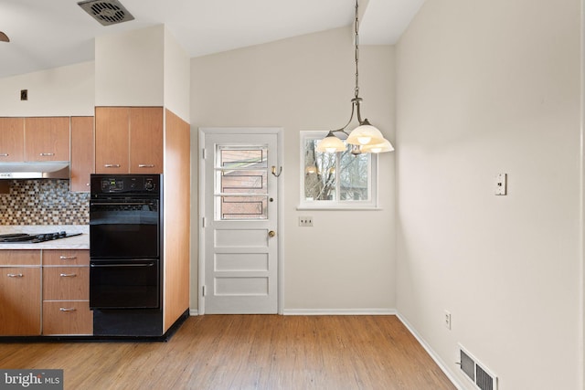 kitchen featuring lofted ceiling, decorative backsplash, visible vents, and under cabinet range hood