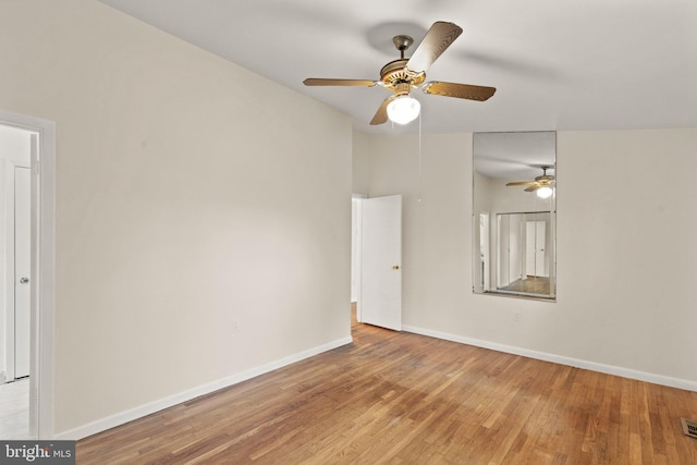 spare room with a ceiling fan, visible vents, baseboards, and wood finished floors