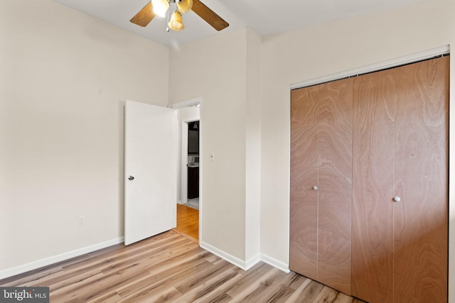 unfurnished bedroom with a closet, wood finished floors, a ceiling fan, and baseboards