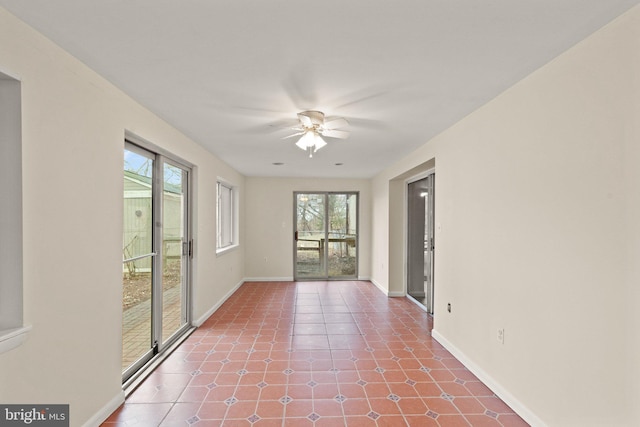 empty room with a ceiling fan, baseboards, and tile patterned floors