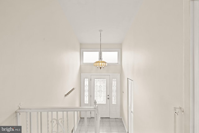 entryway with a high ceiling, light tile patterned flooring, and a notable chandelier