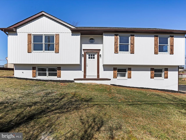 raised ranch featuring a front lawn and brick siding