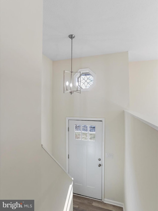 foyer entrance with dark wood-style flooring and an inviting chandelier