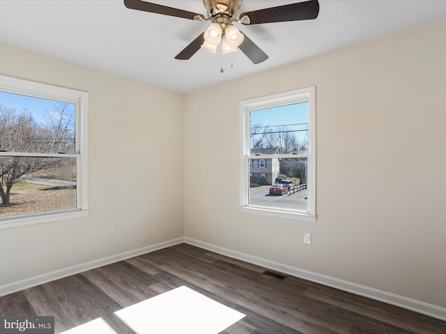 spare room with baseboards, visible vents, and wood finished floors