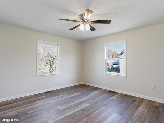 spare room featuring ceiling fan, wood finished floors, visible vents, and baseboards