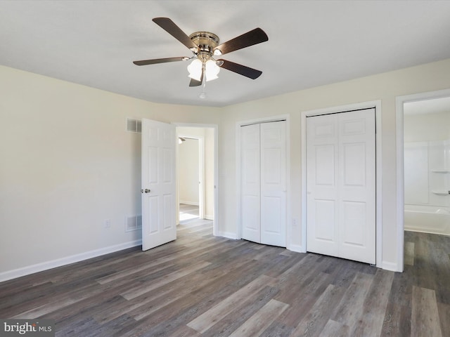 unfurnished bedroom featuring baseboards, visible vents, multiple closets, and wood finished floors