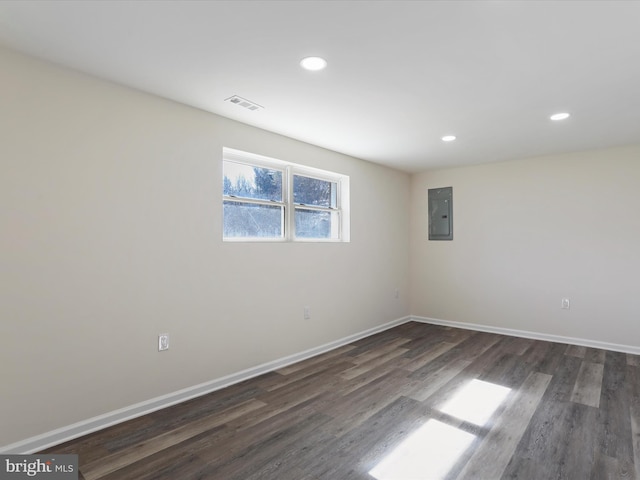 empty room featuring dark wood-style floors, electric panel, visible vents, and baseboards