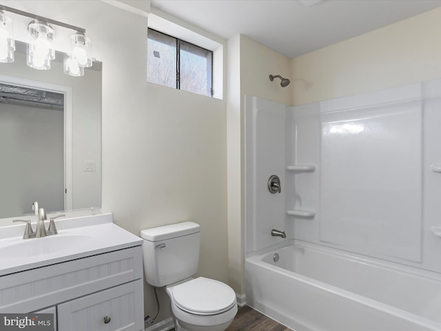 bathroom featuring shower / washtub combination, toilet, vanity, wood finished floors, and baseboards