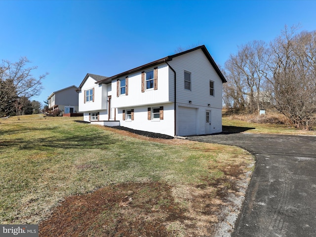 view of front facade with a garage, aphalt driveway, and a front yard