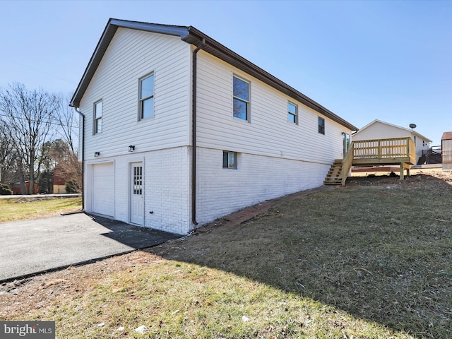 view of property exterior with aphalt driveway, a garage, brick siding, stairs, and a wooden deck