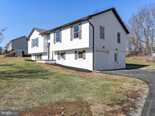 raised ranch with a garage, brick siding, a front lawn, and aphalt driveway