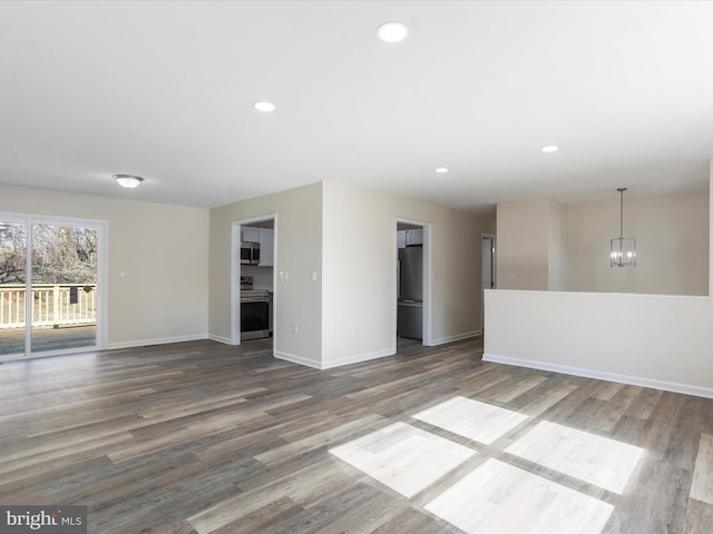 spare room featuring a chandelier, recessed lighting, baseboards, and wood finished floors