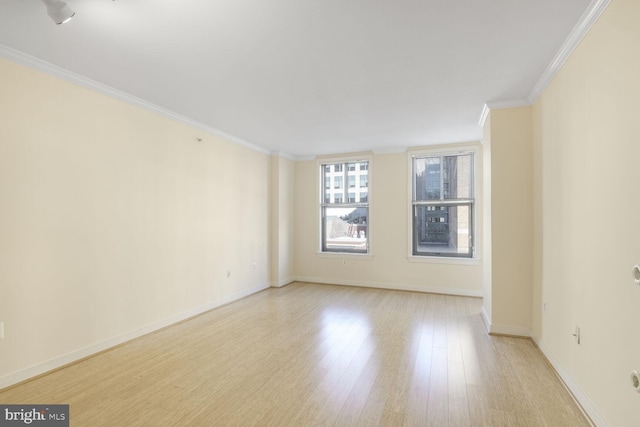 spare room featuring light wood-style flooring, ornamental molding, and baseboards