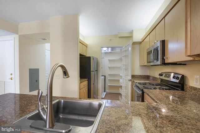 kitchen with stainless steel appliances, a peninsula, a sink, electric panel, and dark stone counters