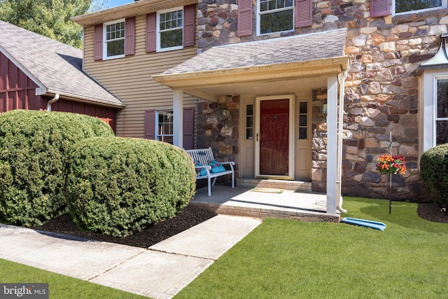 doorway to property with a yard, stone siding, and a porch