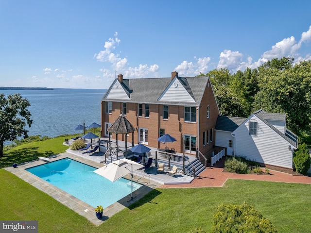 outdoor pool with a yard, a deck with water view, and a diving board