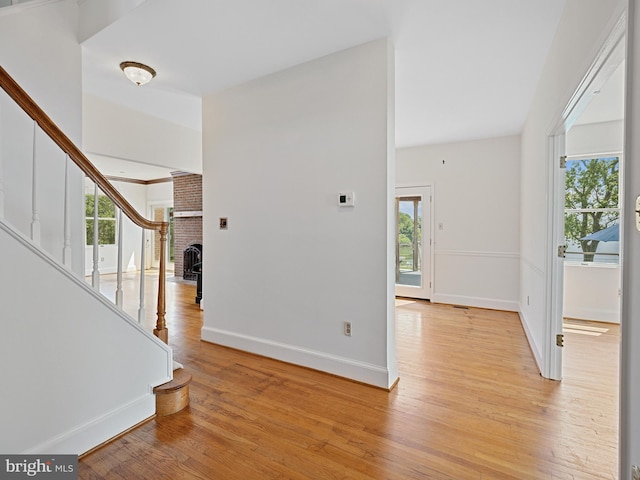 entrance foyer with stairway, light wood-style flooring, a fireplace, and baseboards