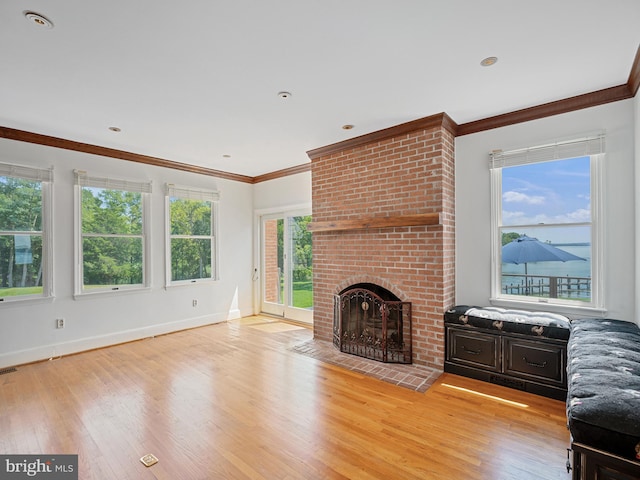 unfurnished living room with baseboards, crown molding, a fireplace, and light wood finished floors