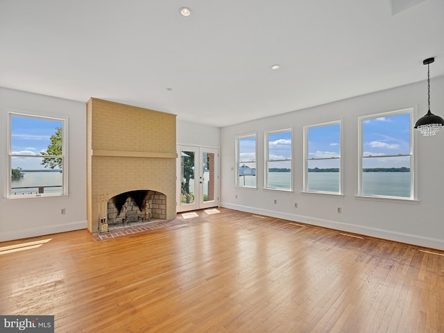 unfurnished living room with light wood-type flooring, baseboards, and a healthy amount of sunlight