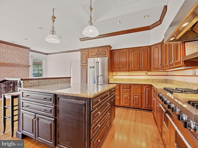 kitchen with a center island with sink, light wood-style flooring, high end fridge, ornamental molding, and wall chimney range hood