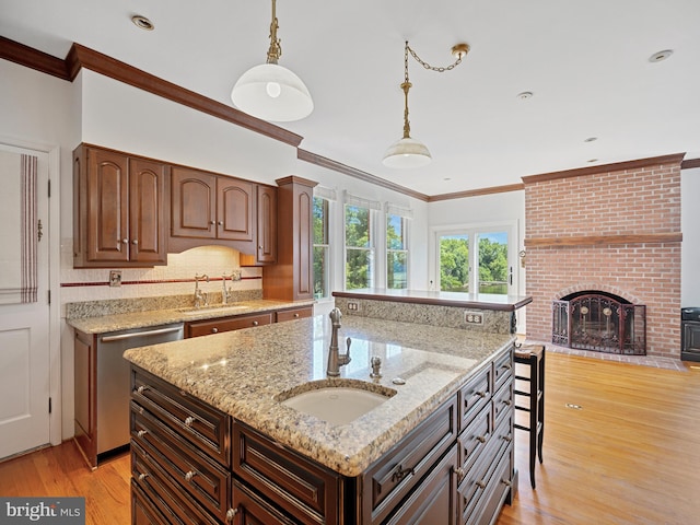 kitchen with a sink, dishwasher, a kitchen island with sink, and light wood finished floors